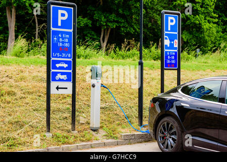 Söderköping, Schweden - 20. Juni 2016: Öffentliche Ladestation für Elektroautos im Einsatz mit dem schwarzen Tesla Auto. Verkehrszeichen sagt abou Stockfoto