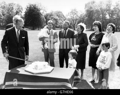 Der Schirmherr der British Heart Foundation, der Herzog von Edinburgh, schneidet auf dem Gelände des Buckingham Palace einen herzförmigen Kuchen, um der Heart Week '85 einen königlichen Sende-off zu geben. Er wird von Lord Soames (hinter dem Herzog) und anderen ehemaligen Herzpatienten beobachtet. Die Gruppe, lebende Beweis für das Thema der Woche "Forschung rettet Leben", sind (l-r) Tania Didwel, 20 Monate und in den Armen ihres Vaters, Peter Rawley, 51, Ann Tooth, 50, Lindsay Stickland, 30, Linda Rooney, 30, und vorne Katherine Bradley, vier, und Elliot Fleisher, acht. *Eingescannte Low-Res aus dem Druck, High-Res auf Anfrage* Stockfoto