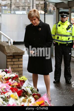 Schottlands erste Ministerin Nicola Sturgeon sieht Blumen, die in der Nähe der Szene des gestrigen Müllwagenabsturzes in Glasgow zurückgelassen wurden. Stockfoto