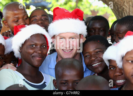 Prinz Harry trägt einen Weihnachtshut mit Waisen aus dem Mants'ase Kinderheim bei einem Besuch in Maseru, Lesotho. Stockfoto