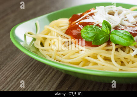 Gekochte Spaghetti mit traditionellen italienischen Tomaten beitragsfrei in eine grüne Platte auf einem Holztisch serviert Stockfoto