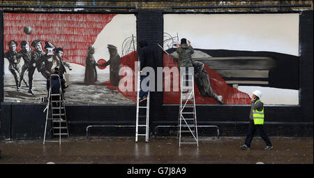 Der deutsche Künstler Sokar Uno (links) setzt ein Graffiti-Kunstwerk mit den britischen Künstlern Zadok und Neunth Seal an der Shoreditch Art Wall im Osten Londons, das im Auftrag von Visit Flanders anlässlich des 100. Jahrestages des Weihnachtsfrieden des Ersten Weltkriegs geschaffen wurde. Stockfoto