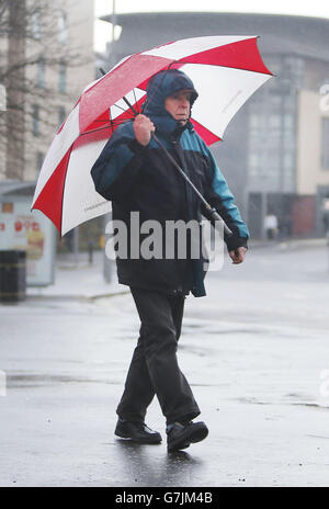 EDS BEMERKT ALTERNATIVE ERNTE EIN Mann mit einem Regenschirm in Glasgow, Schottland, da schlechtes Wetter weiterhin das Vereinigte Königreich trifft. Stockfoto