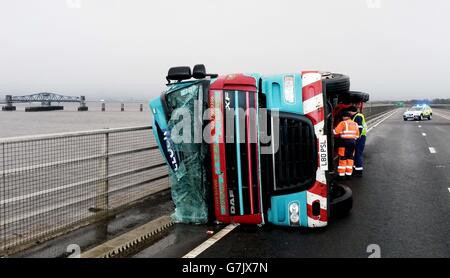 Ein Lastwagen liegt auf seiner Seite, nachdem er bei starkem Wind auf der Clackmannanshire Bridge über den Firth of Forth, Schottland, überwehen wurde, da starke Winde einen weiteren Tag der Störung der britischen Verkehrsnetze gebracht haben, während Warnungen vor heftigen Böen bestehen bleiben, Schnee und Eis über den Großteil des Wochenendes. Stockfoto