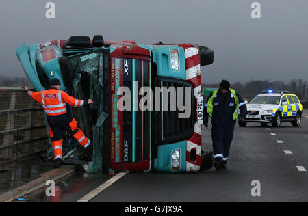 Ein Lastwagen liegt auf seiner Seite, nachdem er bei starkem Wind auf der Clackmannanshire Bridge über den Firth of Forth, Schottland, überwehen wurde, da starke Winde einen weiteren Tag der Störung der britischen Verkehrsnetze gebracht haben, während Warnungen vor heftigen Böen bestehen bleiben, Schnee und Eis über den Großteil des Wochenendes. Stockfoto