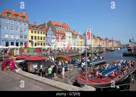 Vater und Sohn eine beschäftigte Nyhavn Kanal mit Touristen und Canal Cruise Boote an einem warmen und sonnigen Sommer überfüllt Samstag anschauen. Bars und Restaurants. Stockfoto