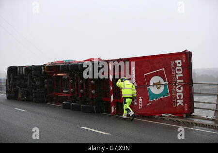 Ein Lastwagen liegt auf seiner Seite, nachdem er bei starkem Wind auf der Clackmannanshire Bridge über den Firth of Forth, Schottland, überwehen wurde, da starke Winde einen weiteren Tag der Störung der britischen Verkehrsnetze gebracht haben, während Warnungen vor heftigen Böen bestehen bleiben, Schnee und Eis über den Großteil des Wochenendes. Stockfoto