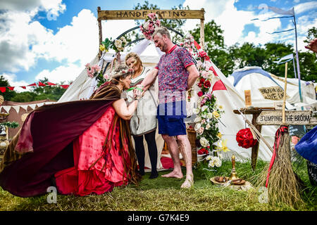 Fiona Wilkins, 33 aus Hartepool und Craig Robson, 41 aus Hartlepool beteiligen sich einer traditionellen Handfasting Zeremonie von Zeremonie Zelebrant Glenda Procter auf dem Glastonbury Festival, würdig Farm in Somerset. PRESSEVERBAND Foto. Finden Sie unter PA Geschichte SHOWBIZ Glastonbury Hochzeit. Bild Datum: Samstag, 25. Juni 2016. Bildnachweis sollte lauten: Ben Birchall/PA Wire Stockfoto