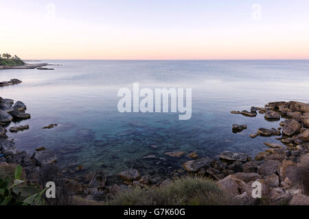 Foto des Meeres in Protaras, Zypern-Insel, mit Felsen und Palmen bei Sonnenuntergang. Stockfoto