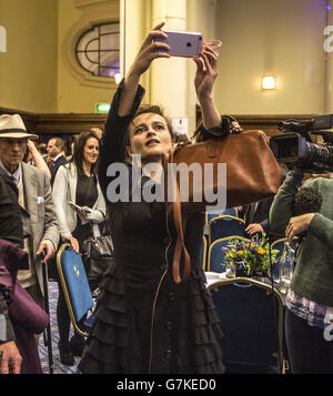Die Schauspielerin Helena Bonham Carter versucht, ein Foto von Premierminister David Cameron (nicht abgebildet) zu machen, während er bei einem Empfang in der Methodist Central Hall, London, von Leuten umgeben ist, die mit Holocaust-Überlebenden sprechen, bevor er zum jährlichen Holocaust Memorial Day gefeiert wird. Stockfoto