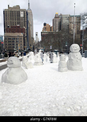 USA, New York: Als der Wintersturm Juno am 27. Januar 2015 aufgibt, bauen New Yorker am Flatiron Plaza, am Rande des Madison Square Park in New York City, eine Gemeinschaft großer Schneemänner auf. NEWZULU/RUSSELL WARSHAY Stockfoto