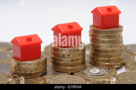 Plastikmodelle von Häusern sitzen auf einem Stapel von einem Pfund-Münzen Stockfoto
