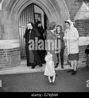 Frau Quintin Hogg, Ehefrau des Wissenschaftsministers, mit ihrer Tochter Katherine, nachdem sie ihre Stimme im Wahllokal der Church of England School in Ponsonby Road, Roehampton, London abgegeben hatte. Im Hintergrund sind Nonnen aus dem nahe gelegenen Marienkonvent zu sehen, die gerade ihre Stimme abgegeben hatten. Stockfoto