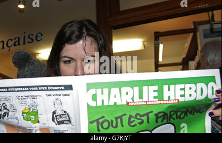 BEACHTEN SIE, DASS EINE Frau außerhalb des französischen Buchladens in South Kensington, London, mit einer Kopie des französischen satirischen Magazins Charlie Hebdo ABGEWECHSELT wird. Stockfoto