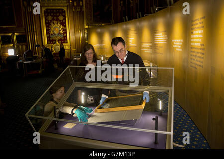 Die Salisbury Cathedral 1215 Kopie der Magna Carta wird in einem Schrank von Chris Woods (rechts), dem Direktor des National Conservation Service, installiert. Neben den anderen drei erhaltenen Originalumwingungen aus Pergament der Magna Carta anlässlich des 800. Jahrestages der Versiegelung der Magna Carta in Runnymede im Jahr 1215 im Robing Room der Queen im Houses of Parliament in London zu sehen. Stockfoto