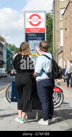 Ein paar lesen eine Santander Kiosk-Aushang in Bloomsbury in London England, UK Stockfoto