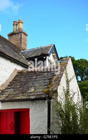 Typisch schottische Cottage mit rote Tür und verwitterten Schieferdach in den Cairngorms National park Stockfoto