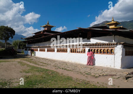 Ein Verehrer an Gebetsmühlen an der Rückseite des Tempels Kyichu Lhakhang, Paro, Bhutan. Stockfoto