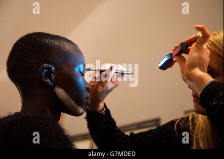 Ein Model lässt ihr Make-up hinter der Bühne aufbringen, bevor die Vivienne Westwood Red Label Herbst/Winter 2015 London Fashion Week im Science Museum in Kensington, West London, gezeigt wird. Stockfoto