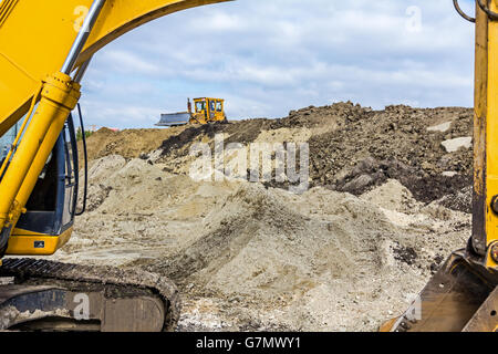 Bagger mit Caterpillar ist bewegten Erde im Freien, Nivellierung Boden. Sehen Sie unter dem Arm des Baggers. Stockfoto