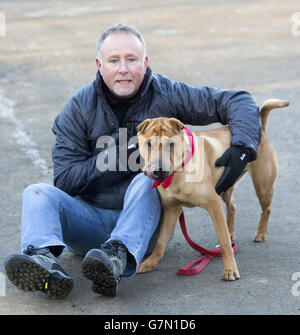 Kai der Hund mit seinem neuen Besitzer Ian Russell in einem schottischen SPCA Büro in Glasgow, nachdem er an einem Bahnhof mit einem Koffer voller seiner Habseligkeiten verlassen wurde. Stockfoto