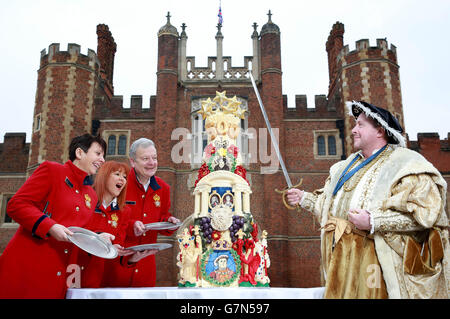 König Henry VIII, gespielt von Chris Bailey, mit Wächter - (von links nach rechts) Caroline Webb, Sheila Dunsmore und Richard Sewell, feiern den 500.Geburtstag des Hampton Court Palastes im Tudor Palast in East Molesey, Surrey, mit einem aufwendig detaillierten fünfstufigen Kuchen, der von Historic Royal Palaces aus Choccywoccydoodah in Auftrag gegeben wurde. Stockfoto