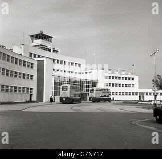 In den 1950er Jahren parkten zwei Doppeldeckerbusse der irischen nationalen Fluggesellschaft Aer Lingus vor dem Eingang des Flughafenterminals in Dublin. Das 1941 eröffnete und von Architekten unter der Leitung von Desmond FitzGerald im Office for Public Works entworfene Design basiert auf dem Design der damaligen Luxusliner. Der Flughafen war in dieser Zeit als Collinstown Airport bekannt und wurde 1937 vom alten Flugplatz Collinstown aus für die Zivilluftfahrt entwickelt, das die Basis des britischen Royal Flying Corps, dem Vorgänger der RAF, war. Der erste Flug dorthin hatte 1940 stattgefunden. Stockfoto