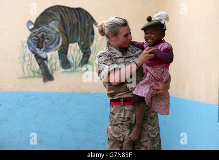 Private Jess Robshaw aus 2 Schotten, spielt mit einem Waisenkind, das ihr Tam O'Shanter trägt, während eines Besuchs im Nanyuki Kinderheim, um den Waisenkindern Geschenke als Soldaten des 2. Bataillons, des Royal Regiment of Scotland, zu spenden. Nehmen Sie an der Übung Askari Storm am Stadtrand von Nanyuki, Kenia, Teil. Stockfoto