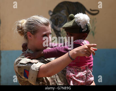 Private Jess Robshaw aus 2 Schotten, spielt mit einem Waisenkind, das ihr Tam O'Shanter trägt, während eines Besuchs im Nanyuki Kinderheim, um den Waisenkindern Geschenke als Soldaten des 2. Bataillons, des Royal Regiment of Scotland, zu spenden. Nehmen Sie an der Übung Askari Storm am Stadtrand von Nanyuki, Kenia, Teil. Stockfoto