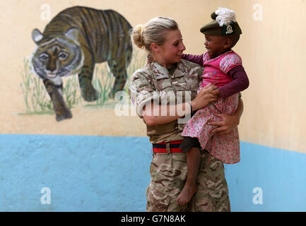 Private Jess Robshaw aus 2 Schotten, spielt mit einem Waisenkind, das ihr Tam O'Shanter trägt, während eines Besuchs im Nanyuki Kinderheim, um den Waisenkindern Geschenke als Soldaten des 2. Bataillons, des Royal Regiment of Scotland, zu spenden. Nehmen Sie an der Übung Askari Storm am Stadtrand von Nanyuki, Kenia, Teil. Stockfoto