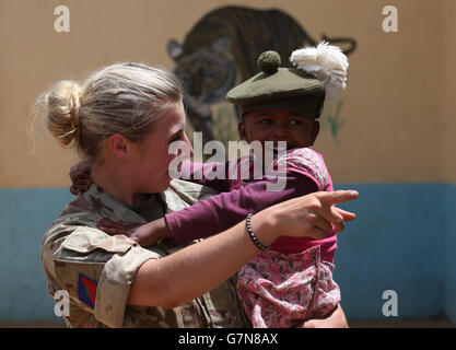 Private Jess Robshaw aus 2 Schotten, spielt mit einem Waisenkind, das ihr Tam O'Shanter trägt, während eines Besuchs im Nanyuki Kinderheim, um den Waisenkindern Geschenke als Soldaten des 2. Bataillons, des Royal Regiment of Scotland, zu spenden. Nehmen Sie an der Übung Askari Storm am Stadtrand von Nanyuki, Kenia, Teil. Stockfoto