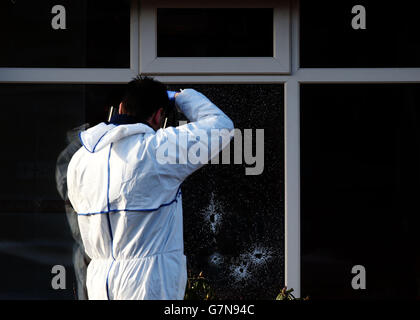 Ein Mitglied des Forensik-Teams von Garda fotografiert Einschusslöcher am Tatort auf der Harty Avenue, Walkinstown, wo ein Mann vor seinem Haus erschossen wurde. Stockfoto