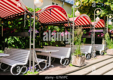 Weißen Bänken vor einem Restaurant mit rot-weiß gestreiften Markisen. Stockfoto