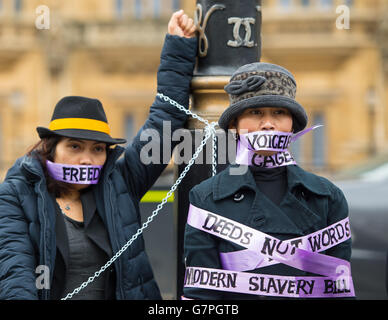 Hausangestellte, die als Frauenrechtlerinnen gekleidet sind, protestieren am Internationalen Frauentag vor dem Parlamentsgebäude in Westminster, im Zentrum Londons, und fordern eine Änderung des Modern Slavery Bill, der es Hausangestellten ermöglichen wird, die Arbeitgeber einmal im Vereinigten Königreich zu wechseln. Stockfoto