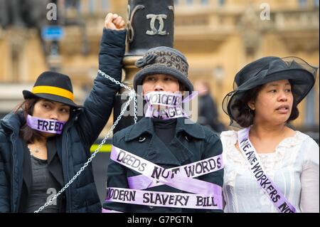 Hausangestellte, die als Frauenrechtlerinnen gekleidet sind, protestieren am Internationalen Frauentag vor dem Parlamentsgebäude in Westminster, im Zentrum Londons, und fordern eine Änderung des Modern Slavery Bill, der es Hausangestellten ermöglichen wird, die Arbeitgeber einmal im Vereinigten Königreich zu wechseln. Stockfoto