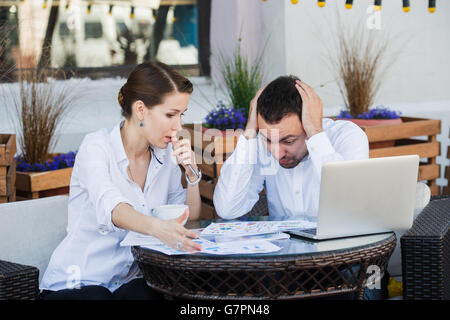 Männlichen und weiblichen Kollegen gemeinsam an ein schwieriges Problem im Café im Freien. Sie sind Ausdruck auf ihren Gesichtern belastet. Stockfoto