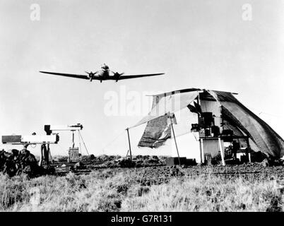 Ein patrouillierender RAAF Dakota fliegt über die Kamera-Beobachtungsposten, komplett mit mobiler Dunkelkammer eingerichtet. Das Lager war ein Objekt von Interesse für die Männer, die an dem Atomtest beteiligt waren. Konteradmiral A. D. Torlesse machte eine besondere Reise in seinem eigenen Flugzeug, um es zu sehen. Sie fotografierten die Explosion der ersten britischen Atomwaffe, die auf den Monte Bello-Inseln vor Australien explodiert war. Die Kameras wurden in grober Reichweite aufgestellt, 55 Meilen vom Zentrum des Atomgebiets entfernt. Stockfoto