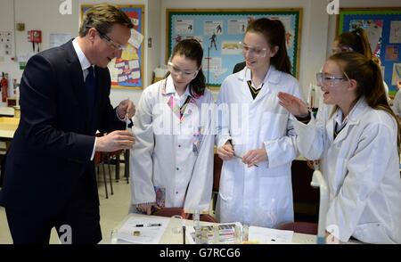 Premierminister David Cameron trifft Schüler und sieht einen Wissenschaftsunterricht bei einem Besuch der Green School for Girls im Westen Londons mit Bildungsminister Nicky Morgan, wo er verkündete, dass die Regierung die Zahl der freien Schulen erhöhen werde, wenn sie die Parlamentswahlen im Mai gewinnen würden. Stockfoto