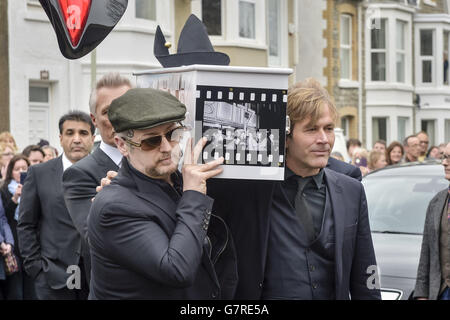 Der mit Visage dekorierte Sarg von Steve Strange wird von Mitgliedern des Spandau Ballet, darunter Steve Norman (vorne rechts) und Boy George (vorne links) vor der All Saints Church, Porthcawl, Wales, aus dem Leichenwagen genommen, wo die Beerdigung des Popstars der 80er Jahre stattfindet. Stockfoto