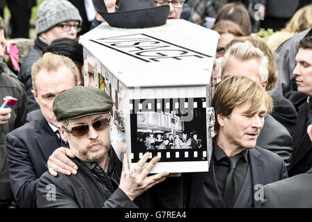 Der mit Visage dekorierte und mit Hut bedeckte Sarg von Steve Strange wird von Mitgliedern des Spandau Ballet, darunter Steve Norman (vorne rechts) und Boy George (vorne links), aus der All Saints Church, Porthcawl, Wales, herausgebracht, wo die Beerdigung des Popstars der 80er Jahre stattfand. Stockfoto