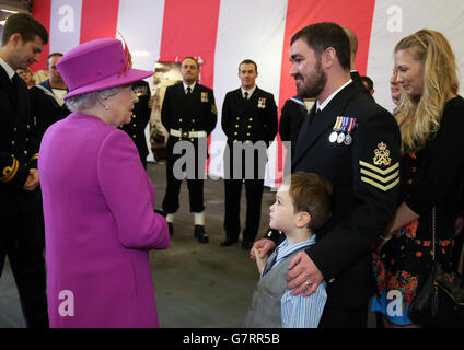 Königin Elizabeth II. (Links) trifft den fünfjährigen Harvey Edmonson und seine Eltern Bryony (rechts) und Alan (zweite rechts) nach fünf Jahren bei einem Treffen mit Familien und Besatzung an Bord der HMS Ocean der Royal Navy auf dem HM Naval Base Devonport in Plymouth, Devon. Stockfoto