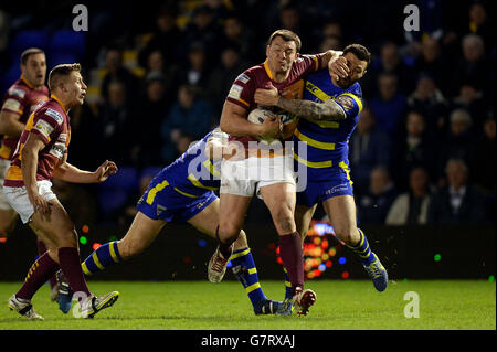 Huddersfield Giants Brett Ferres wird vom Warrington Wolves' Micky Higham (links) und Chris Bridge (rechts) beim ersten Spiel der Utility Super League im Halliwell Jones Stadium, Warrington, getackt. Stockfoto