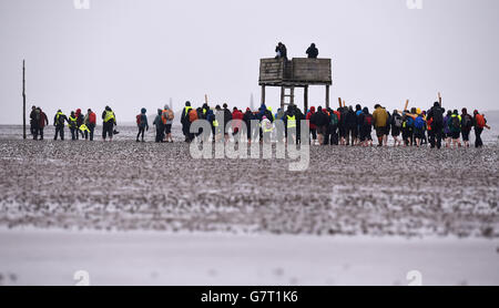 Pilger, die Kreuze tragen, während der jährlichen christlichen Osterwallfahrt am Karfreitag von Beal Sands zur Heiligen Insel Lindisfarne in Northumberland. Stockfoto