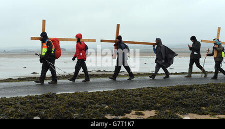 Pilger, die Kreuze tragen, während der jährlichen christlichen Osterwallfahrt am Karfreitag von Beal Sands zur Heiligen Insel Lindisfarne in Northumberland. Stockfoto