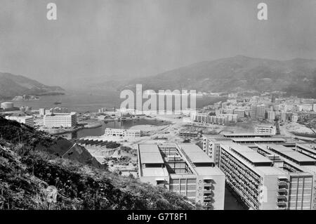 Die neue Wohnanlage wurde teilweise in Tsuen Wan fertiggestellt, die der Eckstein des Kwai Chung-Bauvorhaben sein wird. Im Vordergrund (rechts) befinden sich Umsiedlungshäuser, die auf terrassenförmigem Land gebaut wurden und auf der linken Seite neue Fabriken, die auf Land errichtet wurden, das aus dem Meer zurückgewonnen wurde. Stockfoto