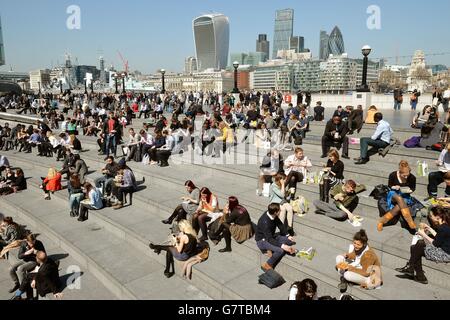 Eine große Menge Stadtarbeiter genießen ihre Mittagspause bei der warmen Frühlingssonne in der Nähe des City Hall und der Tower Bridge im Süden Londons. Stockfoto