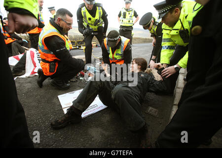 Anti-Trident-Demonstranten, die sich mit Rohrleitungen verbunden haben, haben sie von der Polizei am Südeingang des Marinestützpunktes Clyde, Faslane, abgeschnitten. Stockfoto