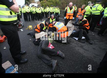 Anti-Trident-Demonstranten, die sich mit Rohrleitungen verbunden haben, haben sie von der Polizei am Südeingang des Marinestützpunktes Clyde, Faslane, abgeschnitten. Stockfoto