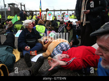 Anti-Trident-Demonstranten sitzen auf der Straße am Eingang des Nordtors am HM Naval Base Clyde, Faslane. Stockfoto