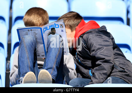 Fans von Coventry lesen das Spieltagsprogramm vor dem Spiel auf den Tribünen. Stockfoto